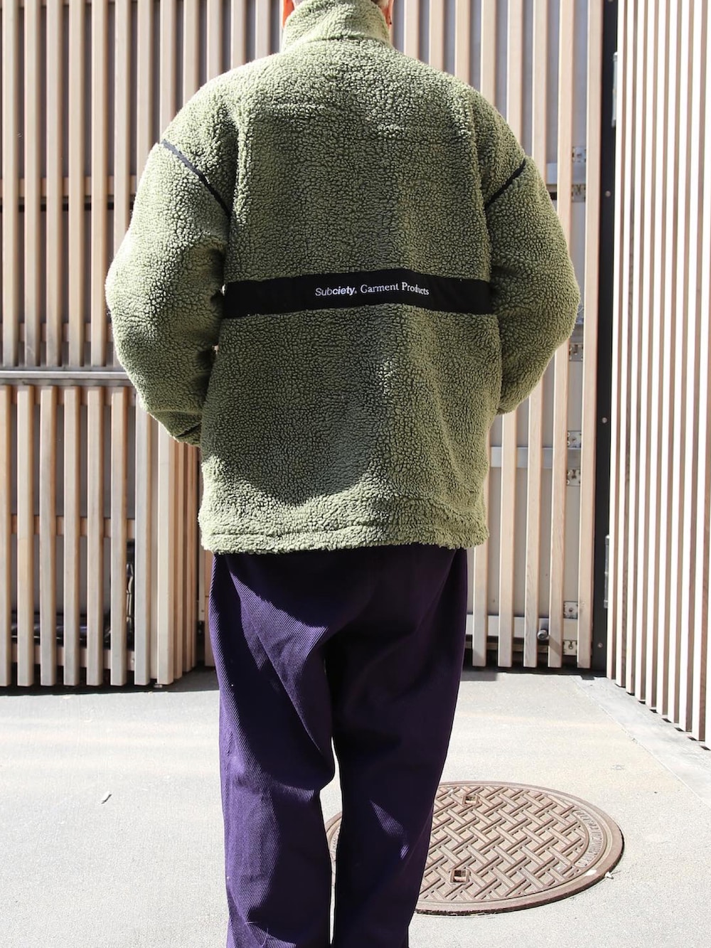 グリーン系のブルゾン、パープル系のその他パンツ、ブラック系のキャップを着用したメンズの秋コーディネートの2枚目の写真