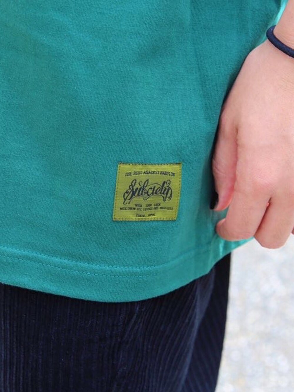 グリーン系のTシャツ/カットソー、ブラック系のハンチング/ベレー帽、ブルー系のサングラスを着用したメンズの夏コーディネートの3枚目の写真