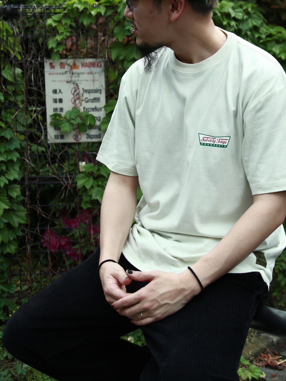ブラック系のスラックス、グリーン系のTシャツ/カットソー、ブラック系のニットキャップ/ビーニーを着用したメンズの春コーディネートの2枚目の写真