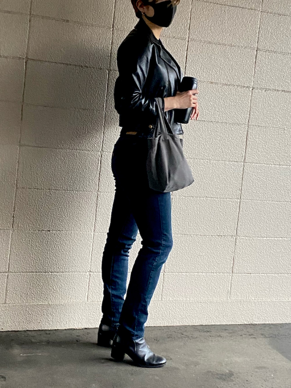 ブルー系のデニムパンツ、ブラック系のブーツ、グレー系のバッグを着用したレディースの秋コーディネートの2枚目の写真