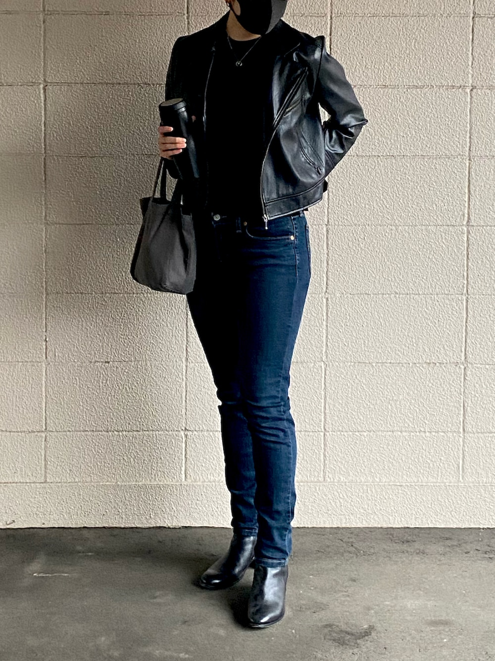 ブルー系のデニムパンツ、ブラック系のブーツ、グレー系のバッグを着用したレディースの秋コーディネートの4枚目の写真