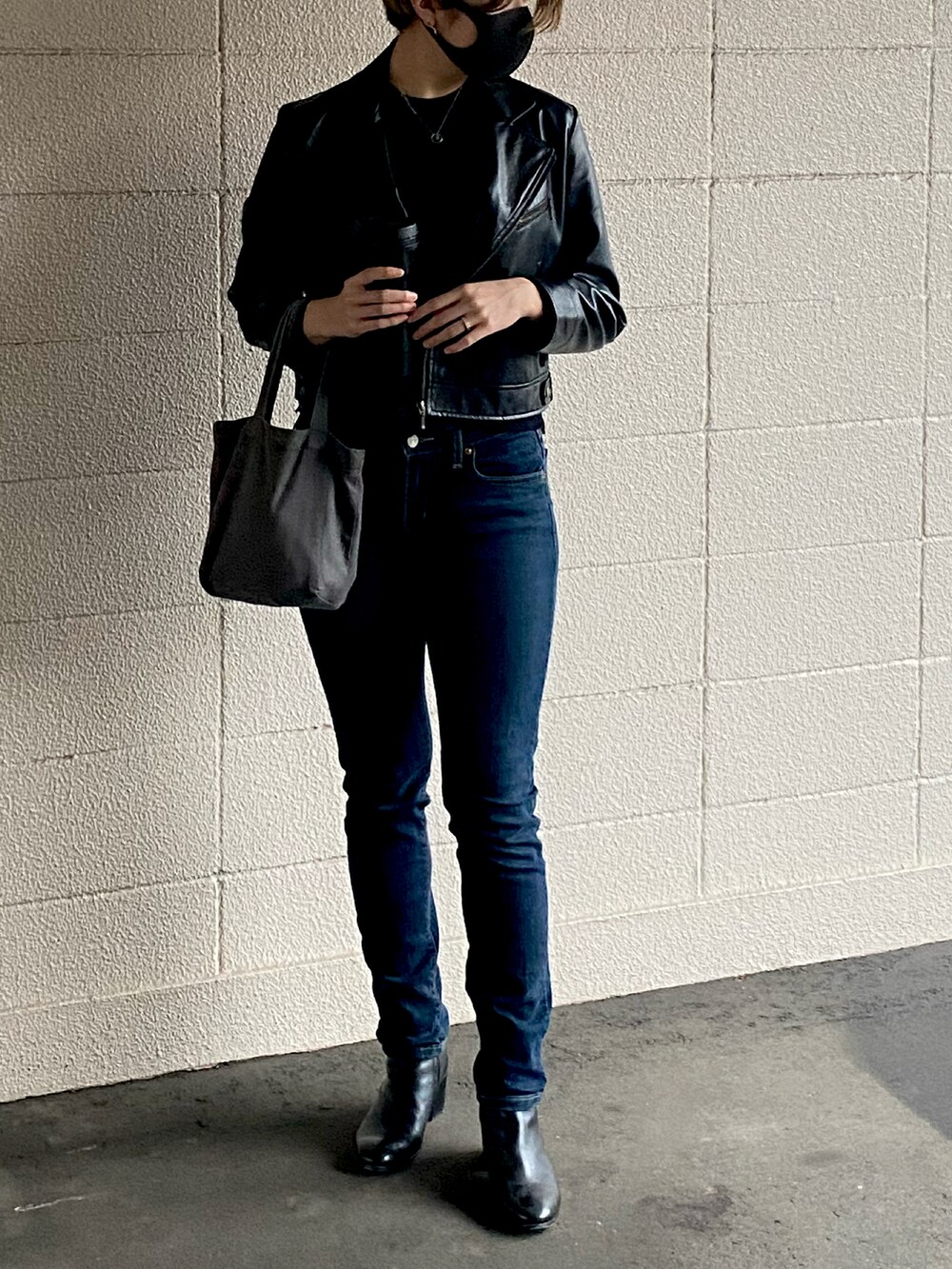 ブルー系のデニムパンツ、ブラック系のブーツ、グレー系のバッグを着用したレディースの秋コーディネートの3枚目の写真
