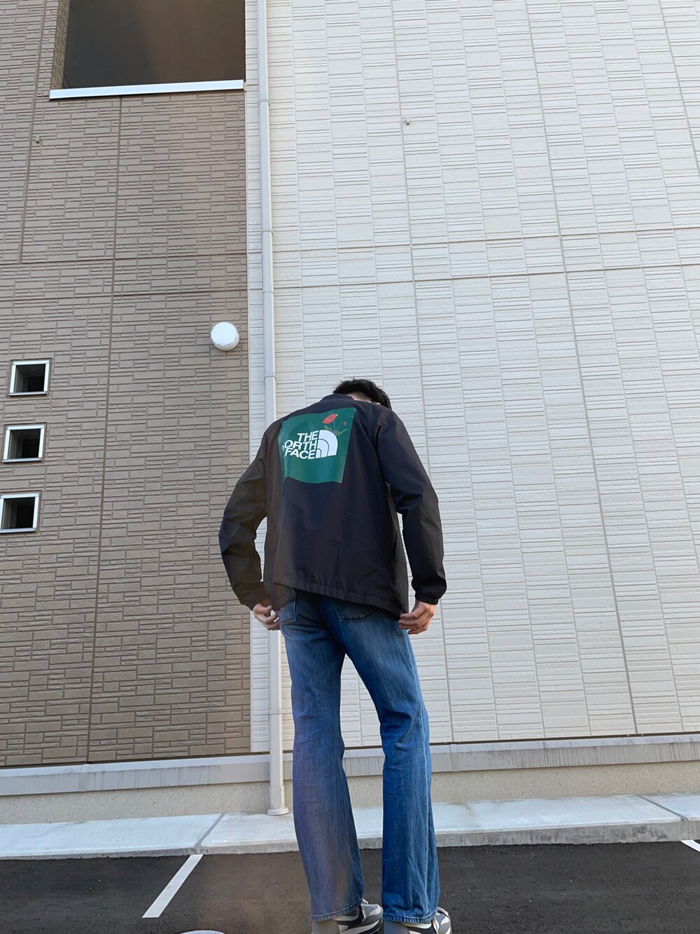 ブルー系のデニムパンツ、ブラック系のブルゾン、グレー系のスニーカーを着用したメンズの春コーディネートの2枚目の写真