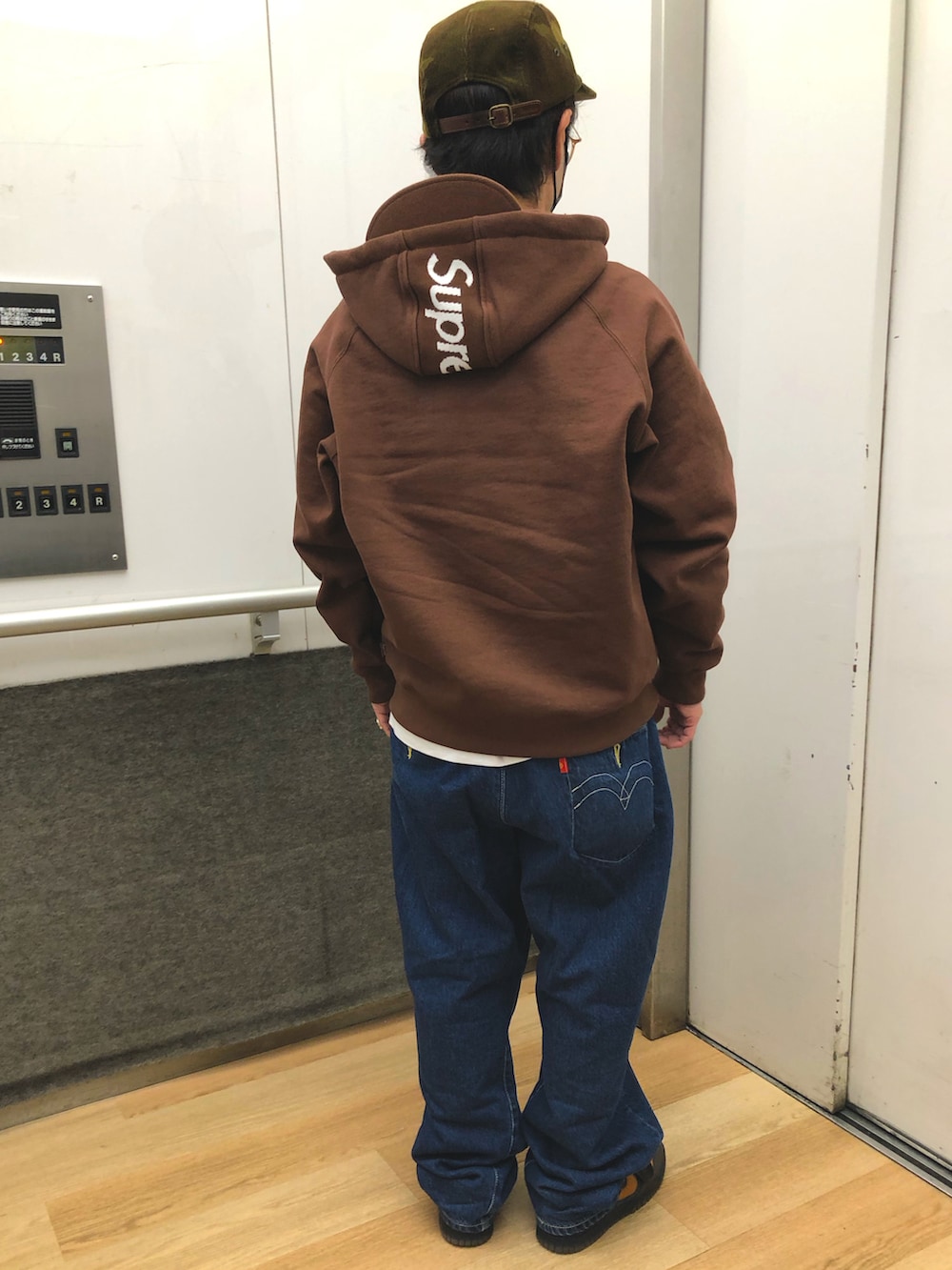 ブルー系のデニムパンツ、ブラウン系のスニーカー、ブラウン系のパーカーを着用したメンズの冬コーディネートの2枚目の写真