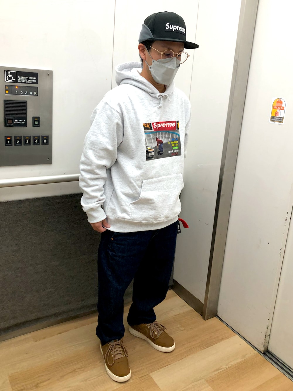 ブルー系のデニムパンツ、ブラウン系のスニーカー、ブラウン系のベストを着用したメンズの秋コーディネートの2枚目の写真