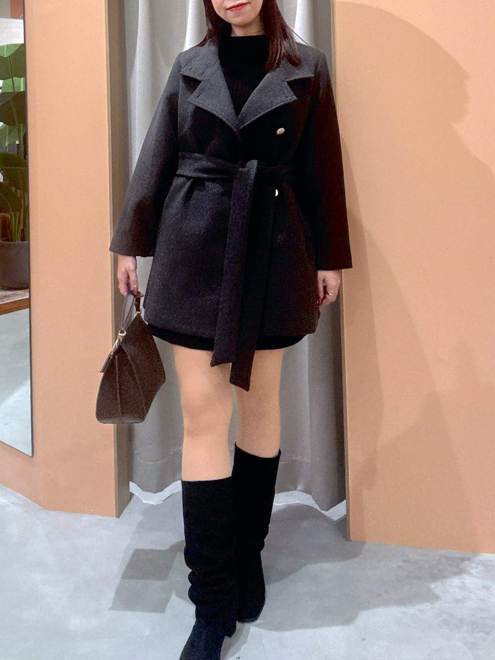 ブラック系のワンピース、グレー系のジャケット/アウター、ブラック系のブーツを着用したレディースの秋コーディネートの2枚目の写真