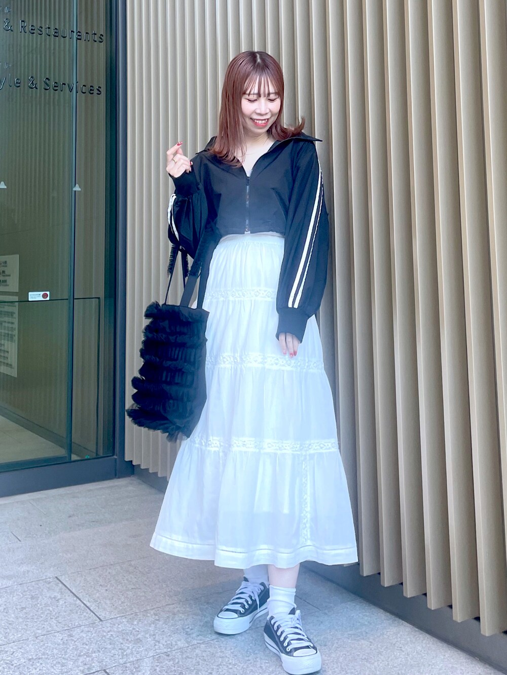 ホワイト系のスカート、ブラック系のスニーカー、ブラック系のトートバッグを着用したレディースの春コーディネートの4枚目の写真