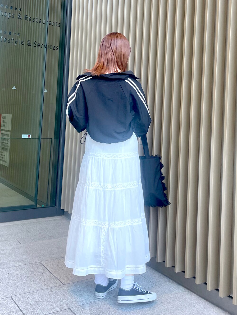 ホワイト系のスカート、ブラック系のスニーカー、ブラック系のトートバッグを着用したレディースの春コーディネートの3枚目の写真