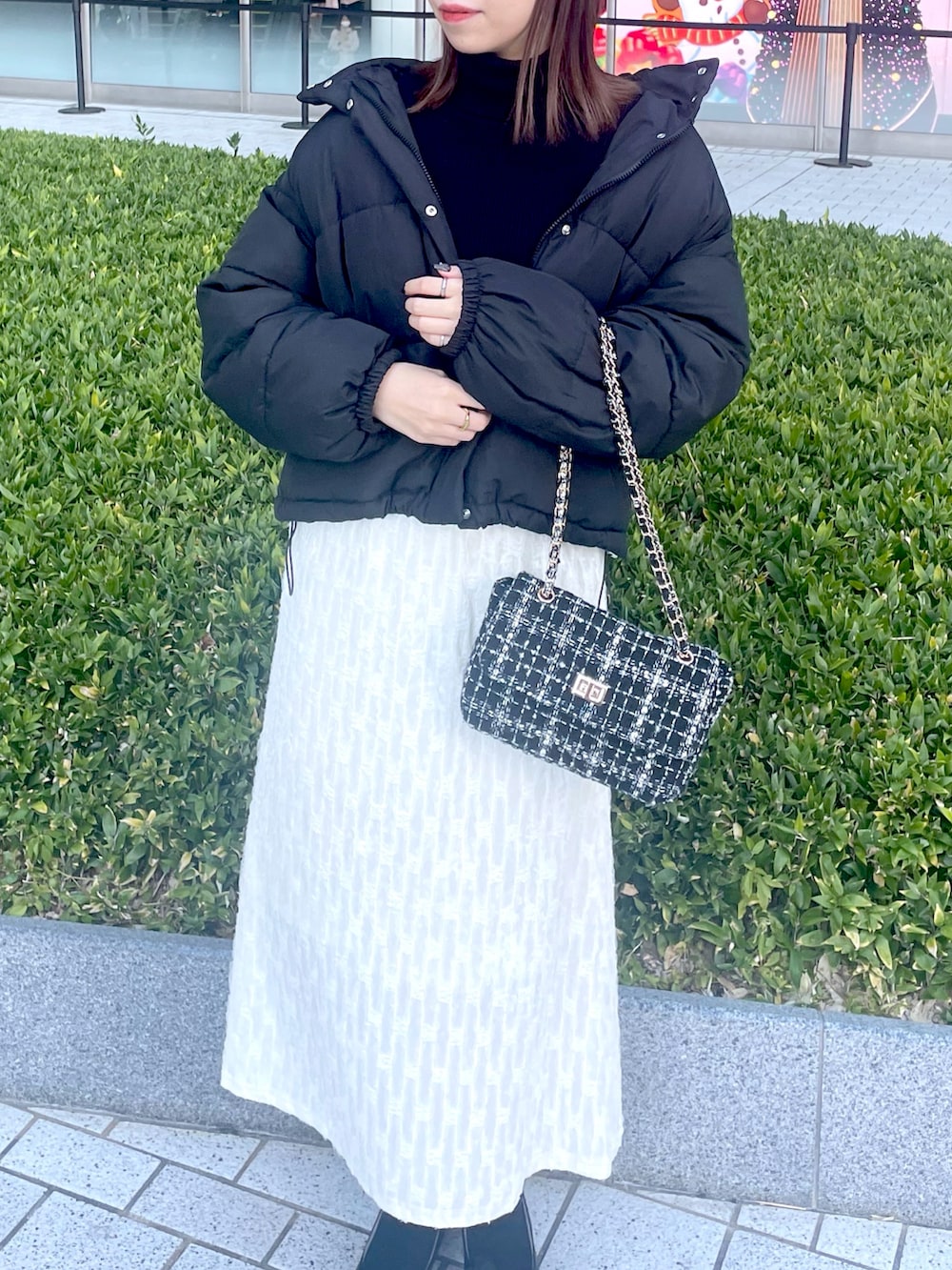 ブラック系のダウンジャケット/コート、ブラック系のニット/セーター、ホワイト系のスカートを着用したレディースの冬コーディネートの2枚目の写真