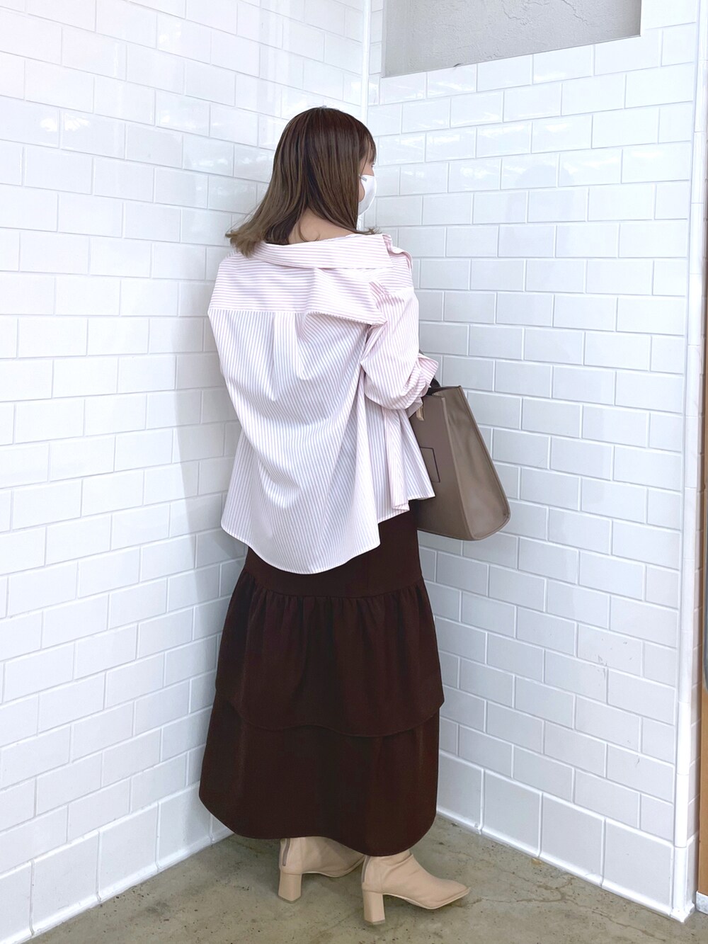 ブラウン系のワンピース、ピンク系のシャツ/ブラウス、ベージュ系のショルダーバッグを着用したレディースの冬コーディネートの2枚目の写真