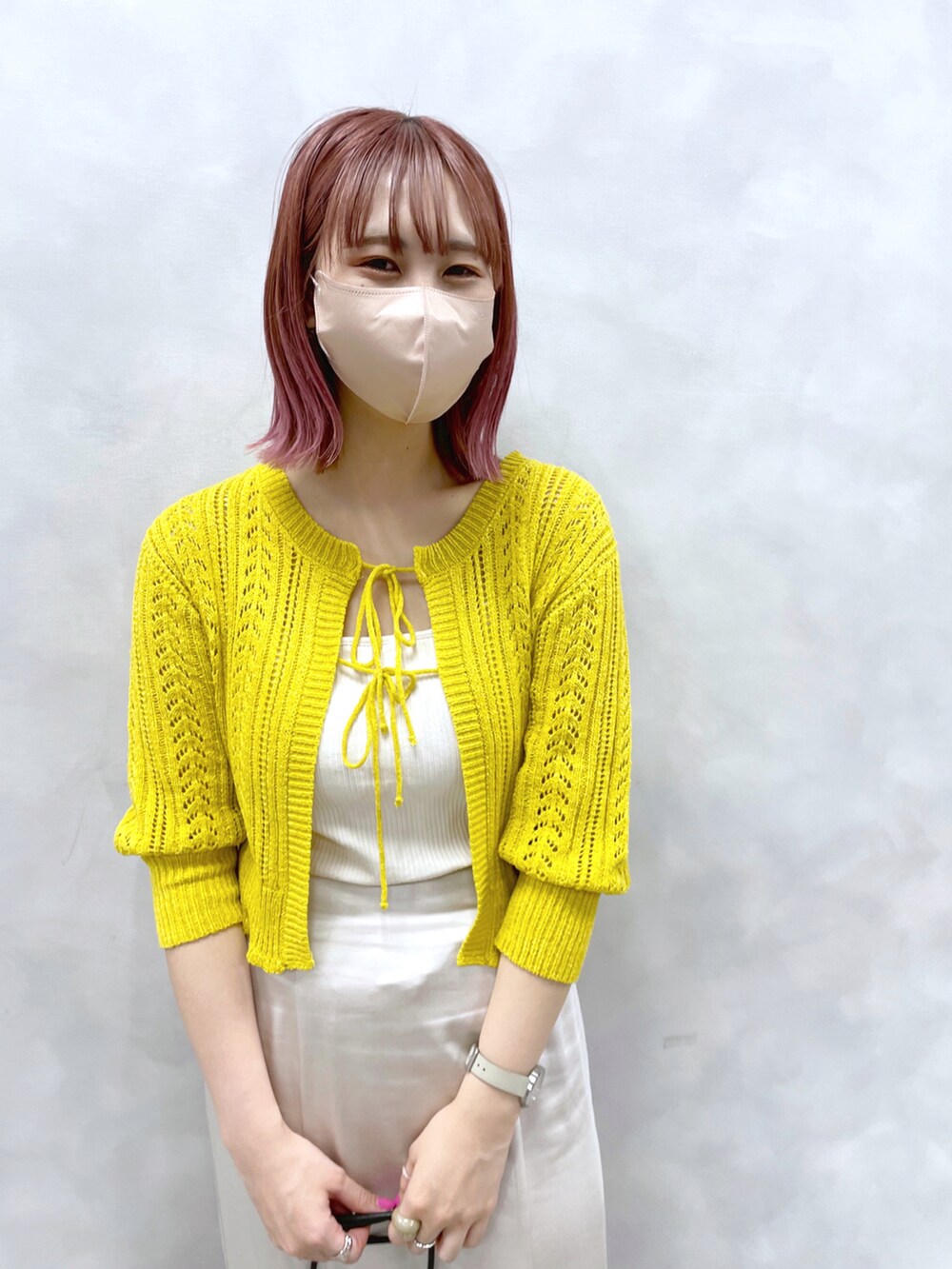 イエロー系のカーディガン/ボレロ、ホワイト系のスカート、ベージュ系のショルダーバッグを着用したレディースの春コーディネートの2枚目の写真