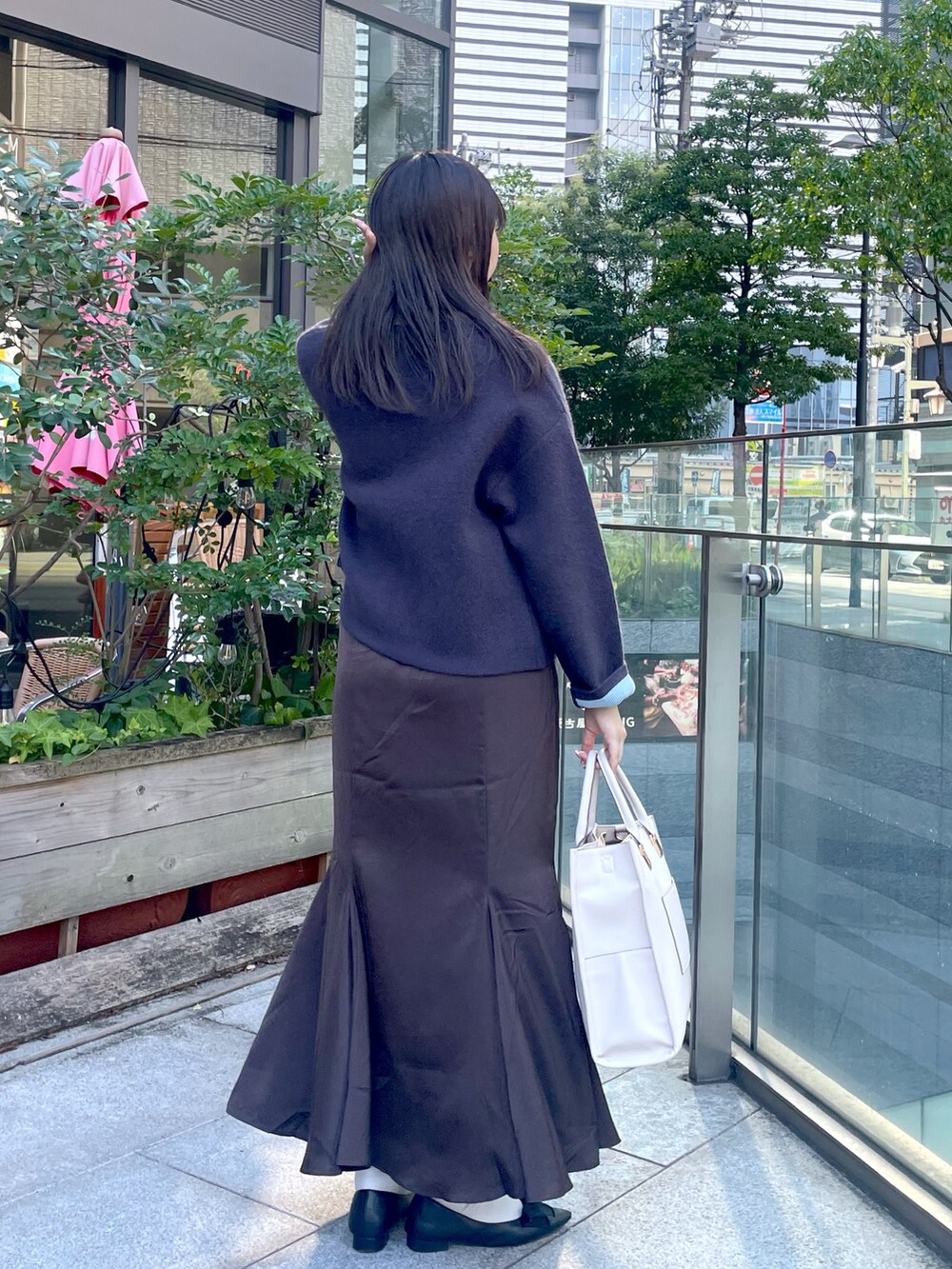 グレー系のノーカラージャケット、ブラウン系のスカート、ブラック系のパンプスを着用したレディースの秋コーディネートの2枚目の写真