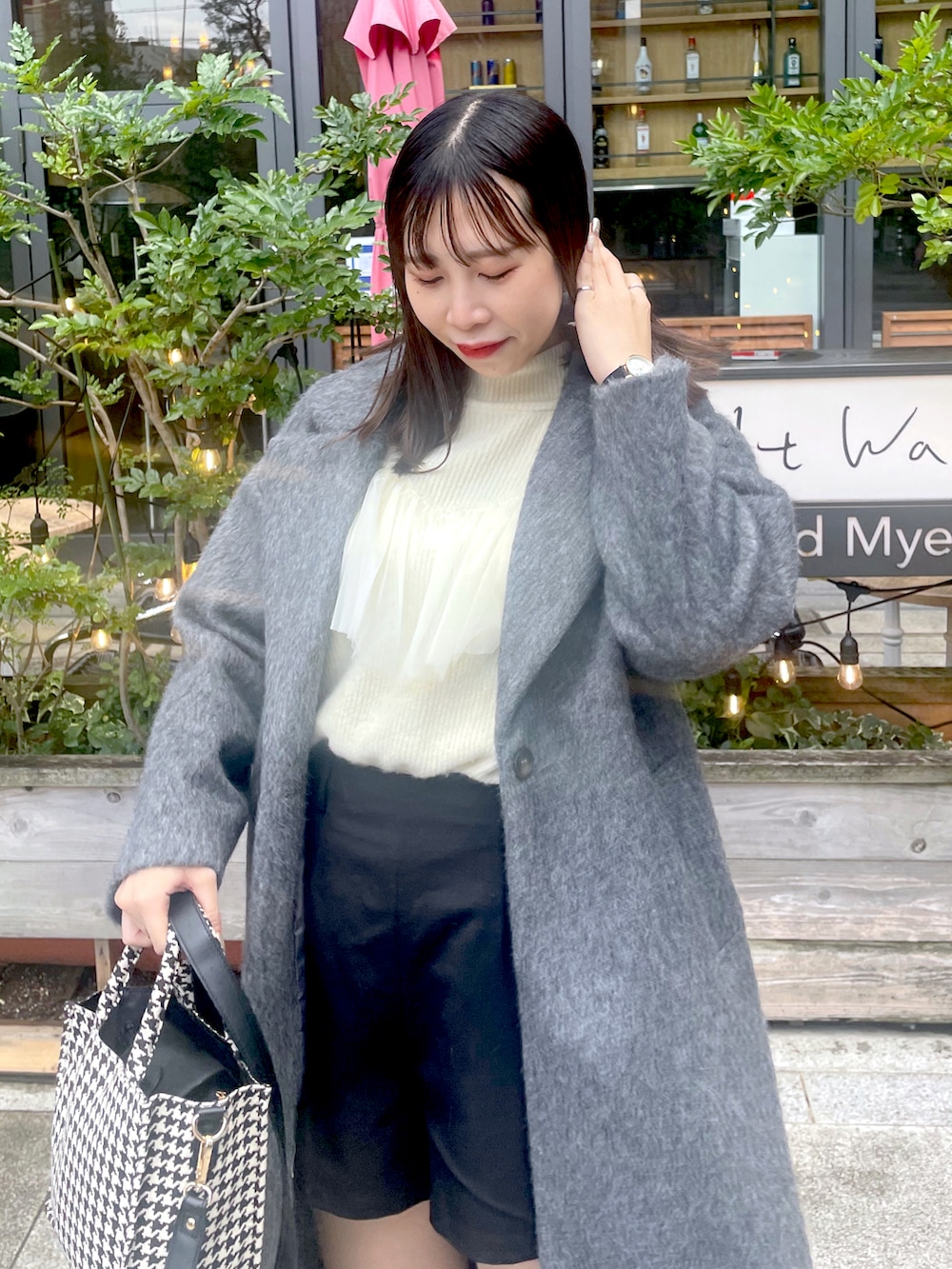 ホワイト系のニット/セーター、グレー系のチェスターコート、ブラック系のブーツを着用したレディースの冬コーディネートの2枚目の写真