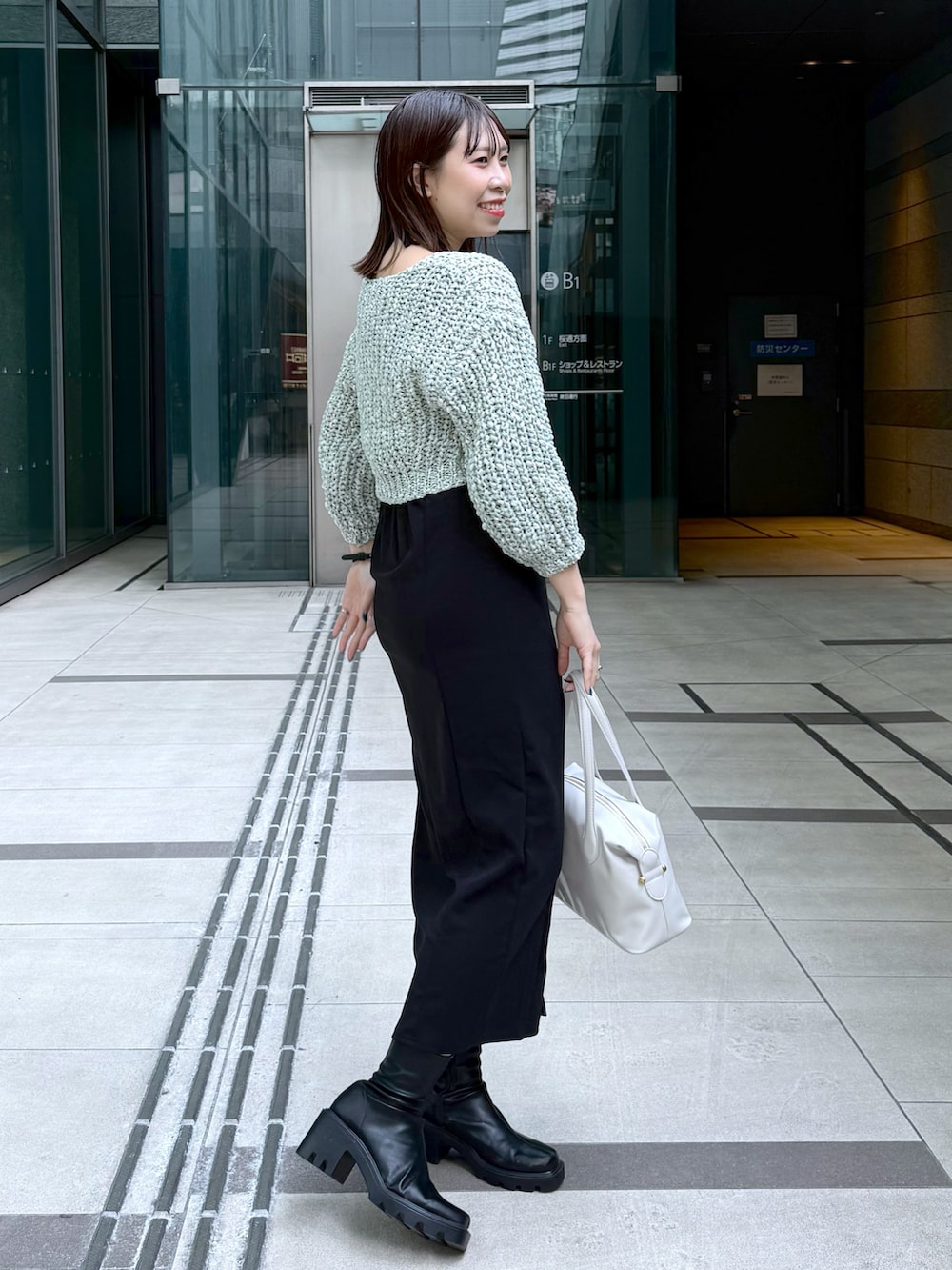 ブラック系のワンピース、グリーン系のカーディガン/ボレロを着用したレディースの春コーディネートの2枚目の写真