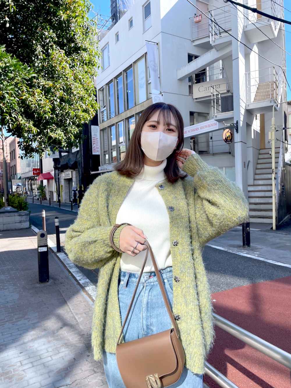 ブルー系のデニムパンツ、ホワイト系のニット/セーター、グリーン系のノーカラーコートを着用したレディースの秋コーディネートの2枚目の写真