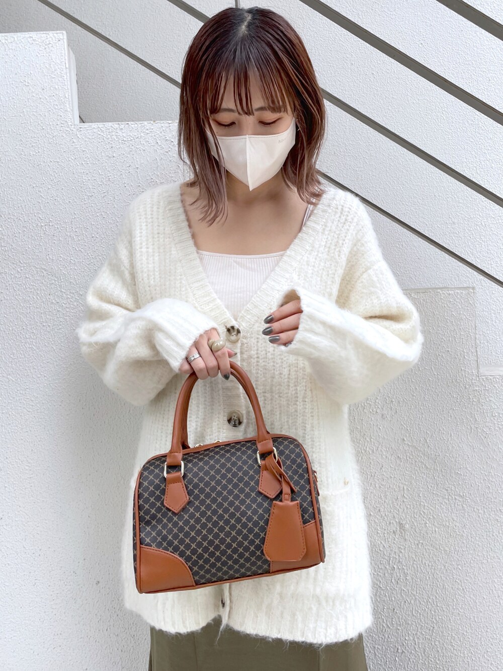 ホワイト系のカーディガン/ボレロ、グリーン系のスカート、ブラック系のブーツを着用したレディースの冬コーディネートの2枚目の写真