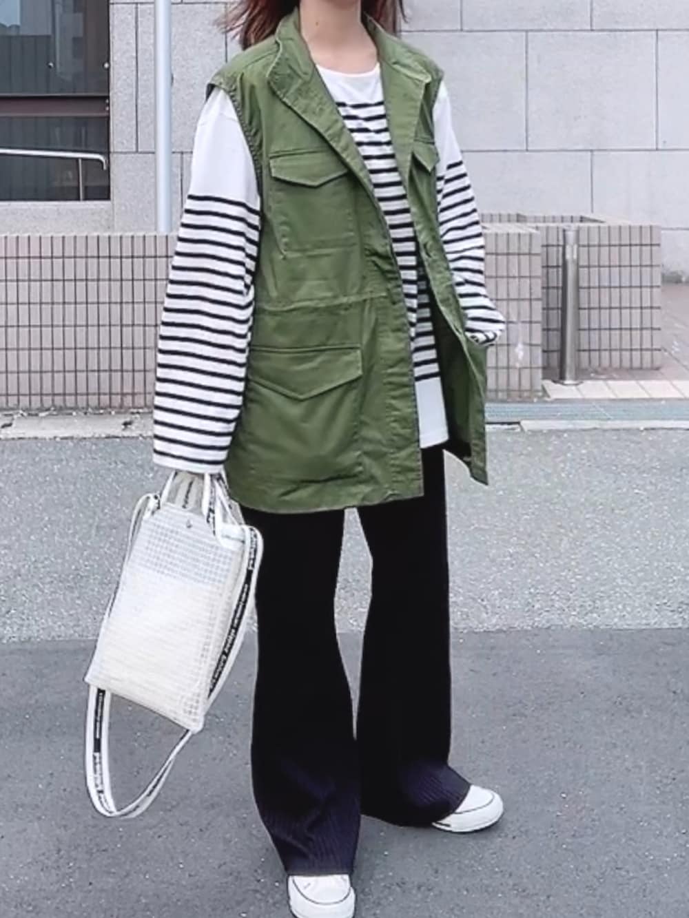 グリーン系のベスト、ホワイト系のTシャツ/カットソー、ホワイト系のショルダーバッグを着用したレディースの春コーディネートの2枚目の写真