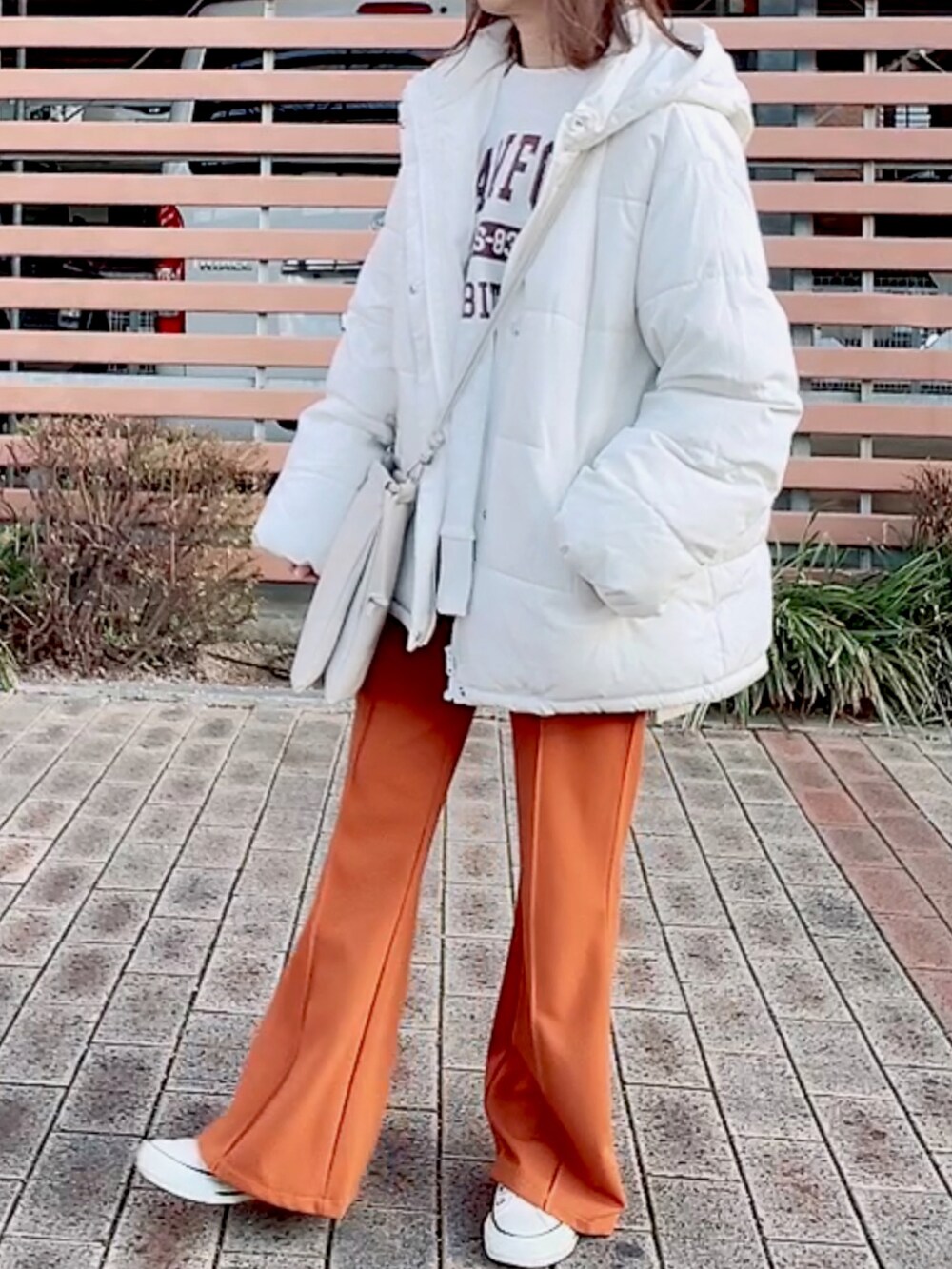 ホワイト系のダウンジャケット/コート、ベージュ系のスウェット、ホワイト系のショルダーバッグを着用したレディースの冬コーディネートの2枚目の写真