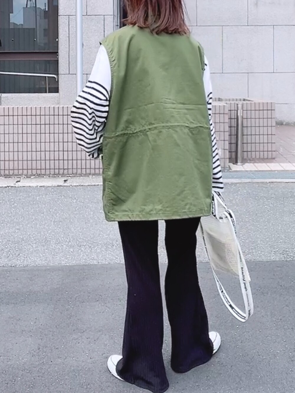 グリーン系のベスト、ホワイト系のTシャツ/カットソー、ホワイト系のショルダーバッグを着用したレディースの春コーディネートの3枚目の写真