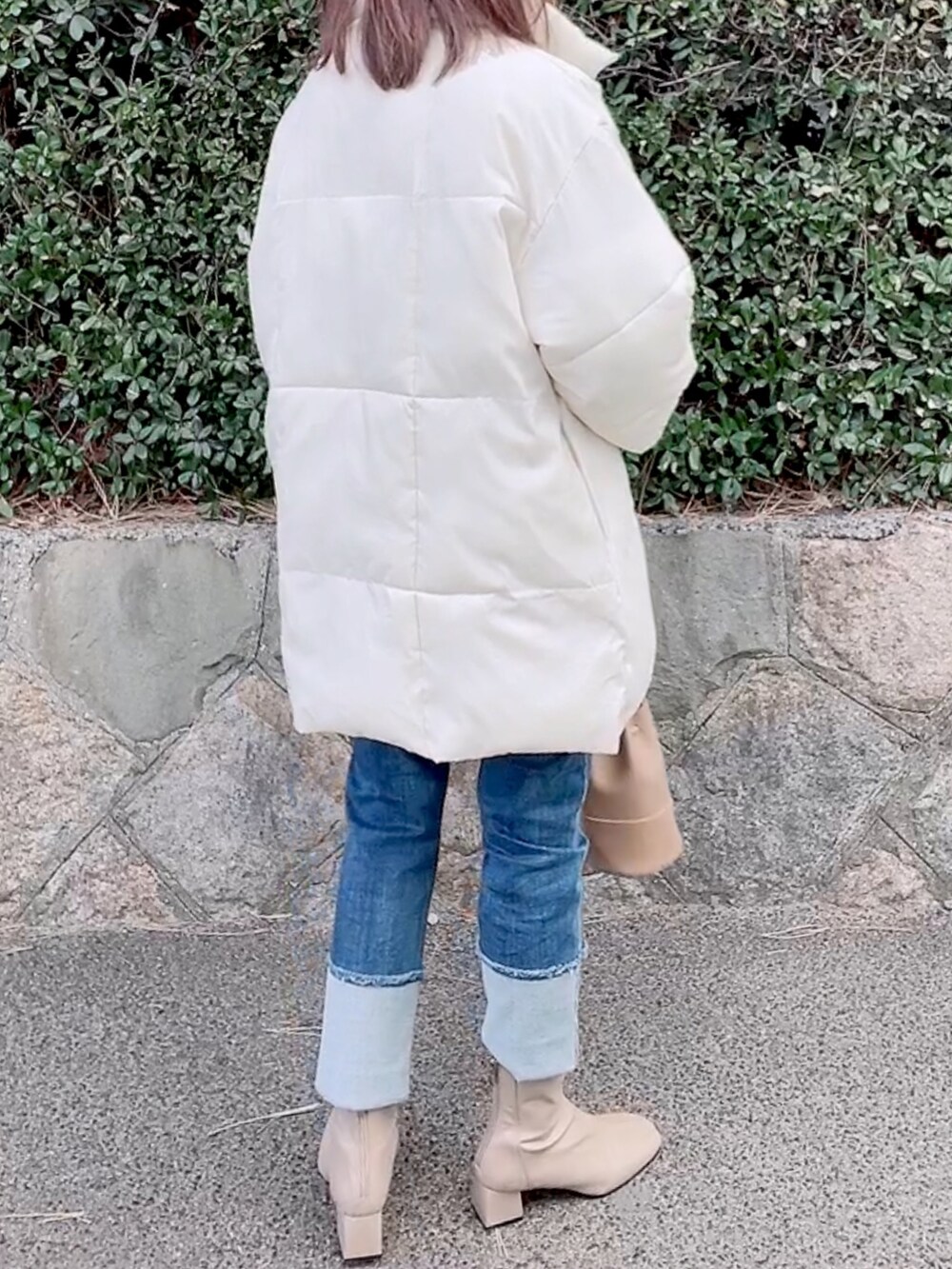 ホワイト系のダウンジャケット/コート、ブルー系のニット/セーター、ブルー系のデニムパンツを着用したレディースの冬コーディネートの4枚目の写真