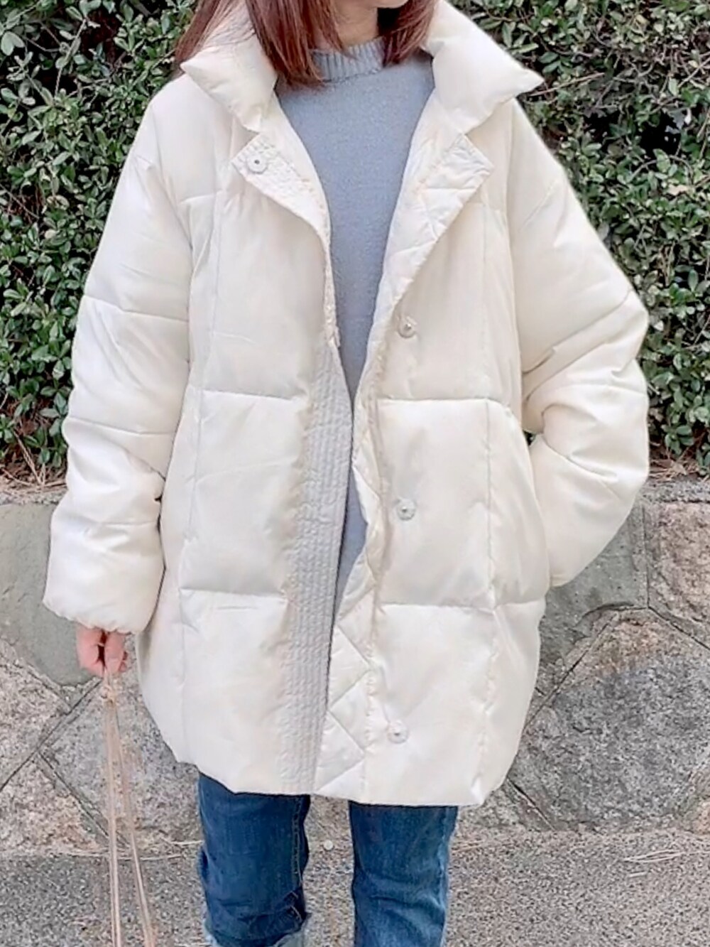 ホワイト系のダウンジャケット/コート、ブルー系のニット/セーター、ブルー系のデニムパンツを着用したレディースの冬コーディネートの2枚目の写真