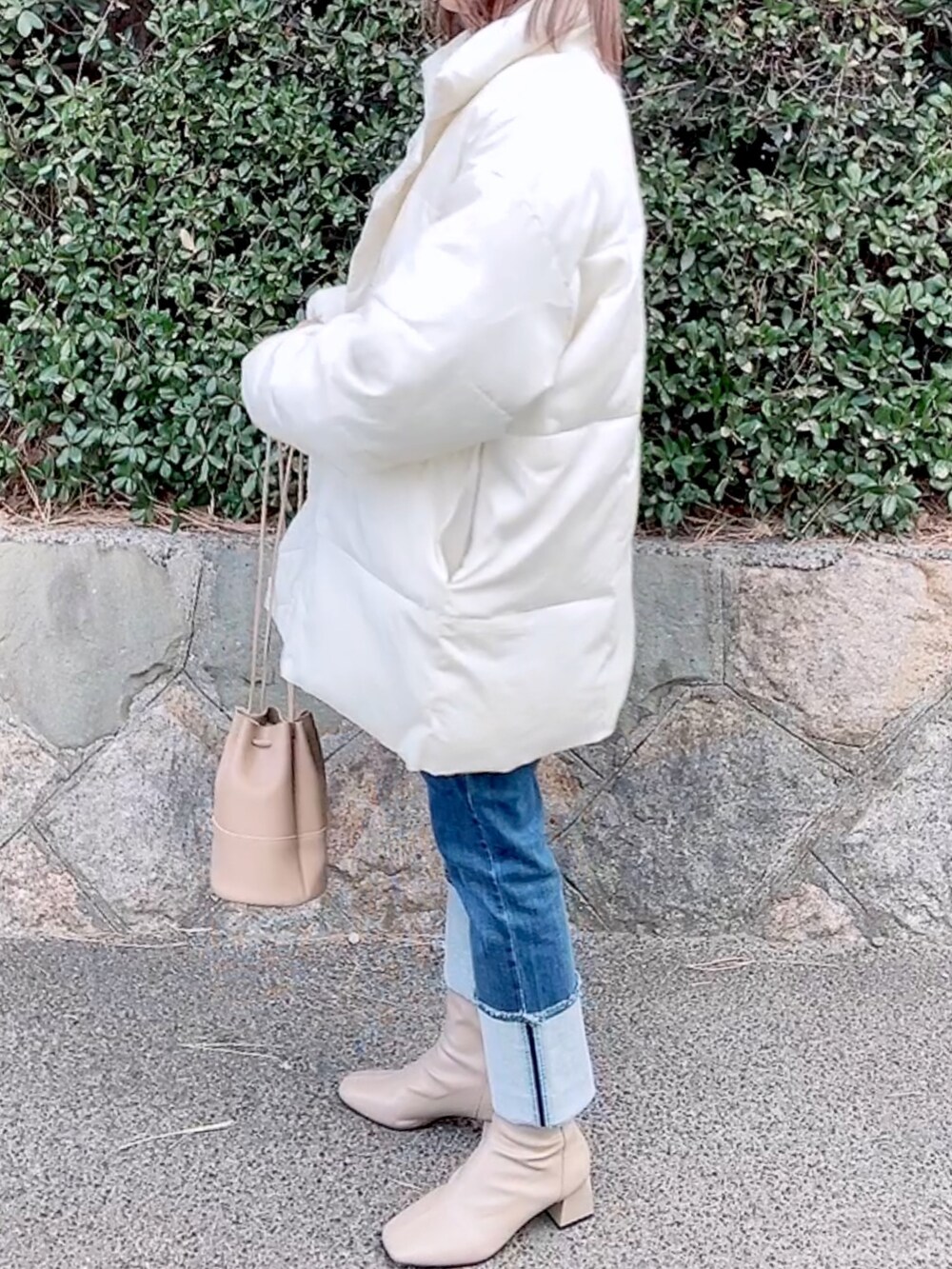 ホワイト系のダウンジャケット/コート、ブルー系のニット/セーター、ブルー系のデニムパンツを着用したレディースの冬コーディネートの3枚目の写真