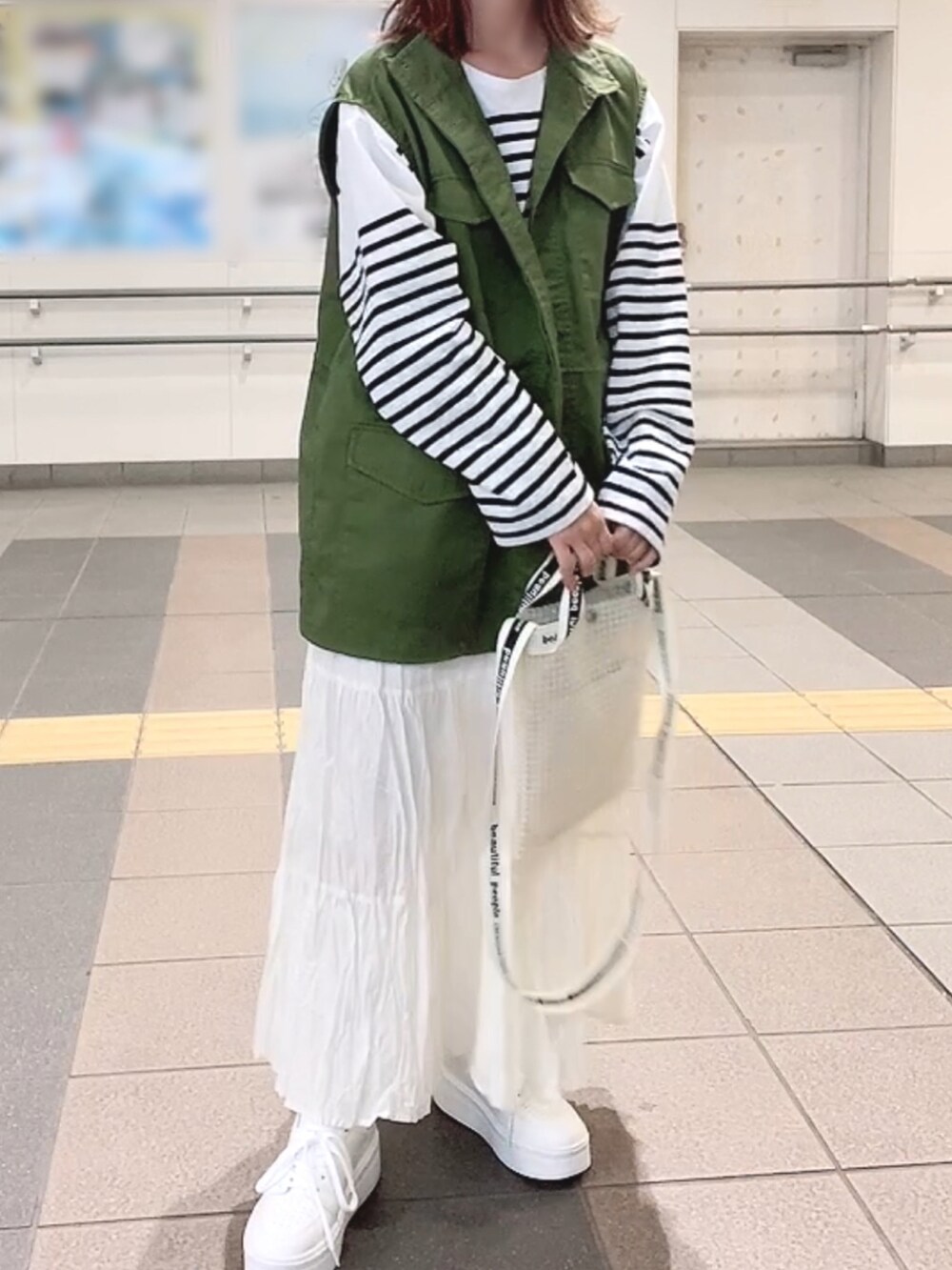 グリーン系のベスト、ホワイト系のTシャツ/カットソー、ホワイト系のスカートを着用したレディースの春コーディネートの2枚目の写真