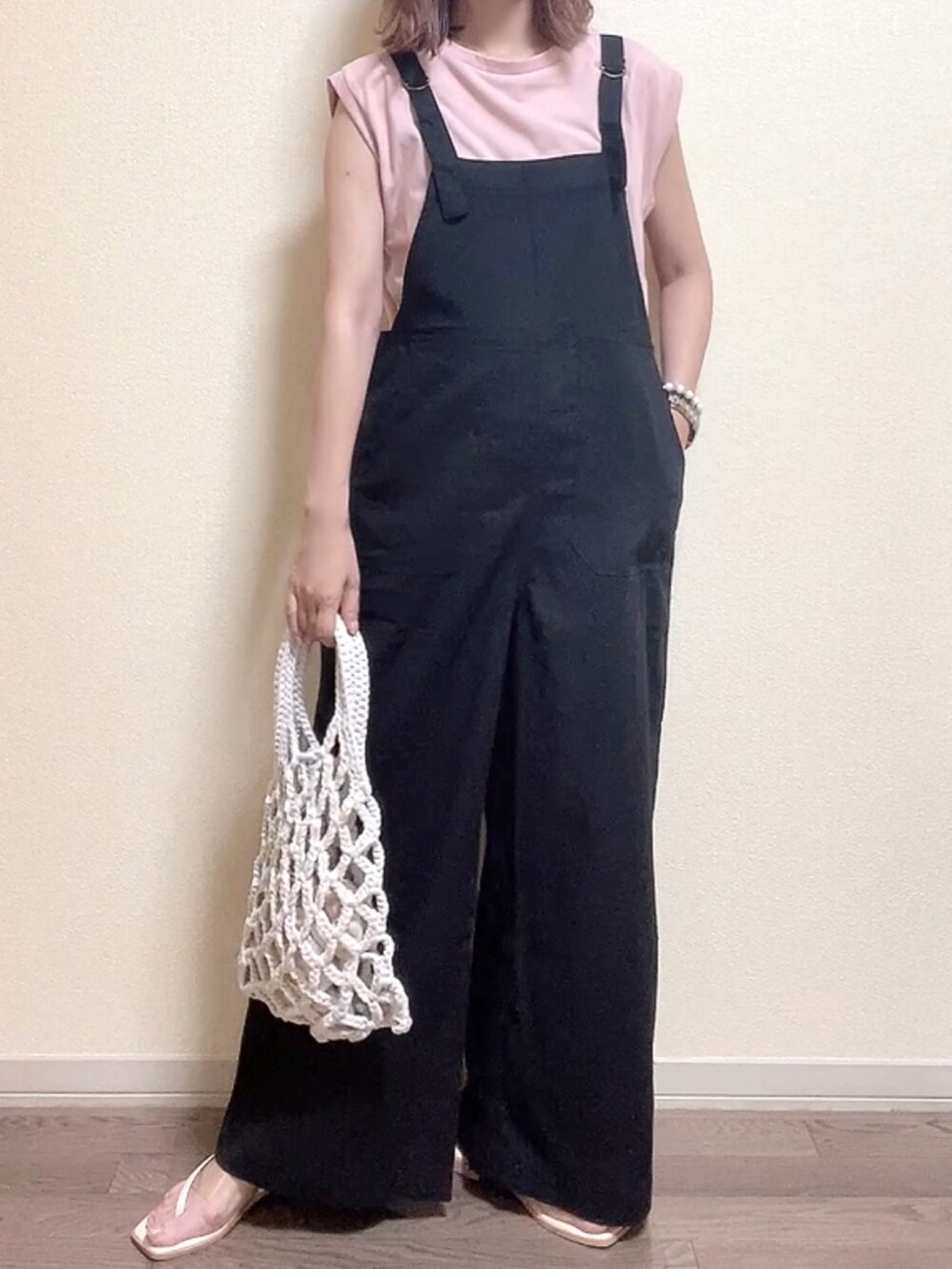 ピンク系のTシャツ/カットソー、ブラック系のサロペット/オーバーオール、ホワイト系のハンドバッグを着用したレディースの夏コーディネートの3枚目の写真