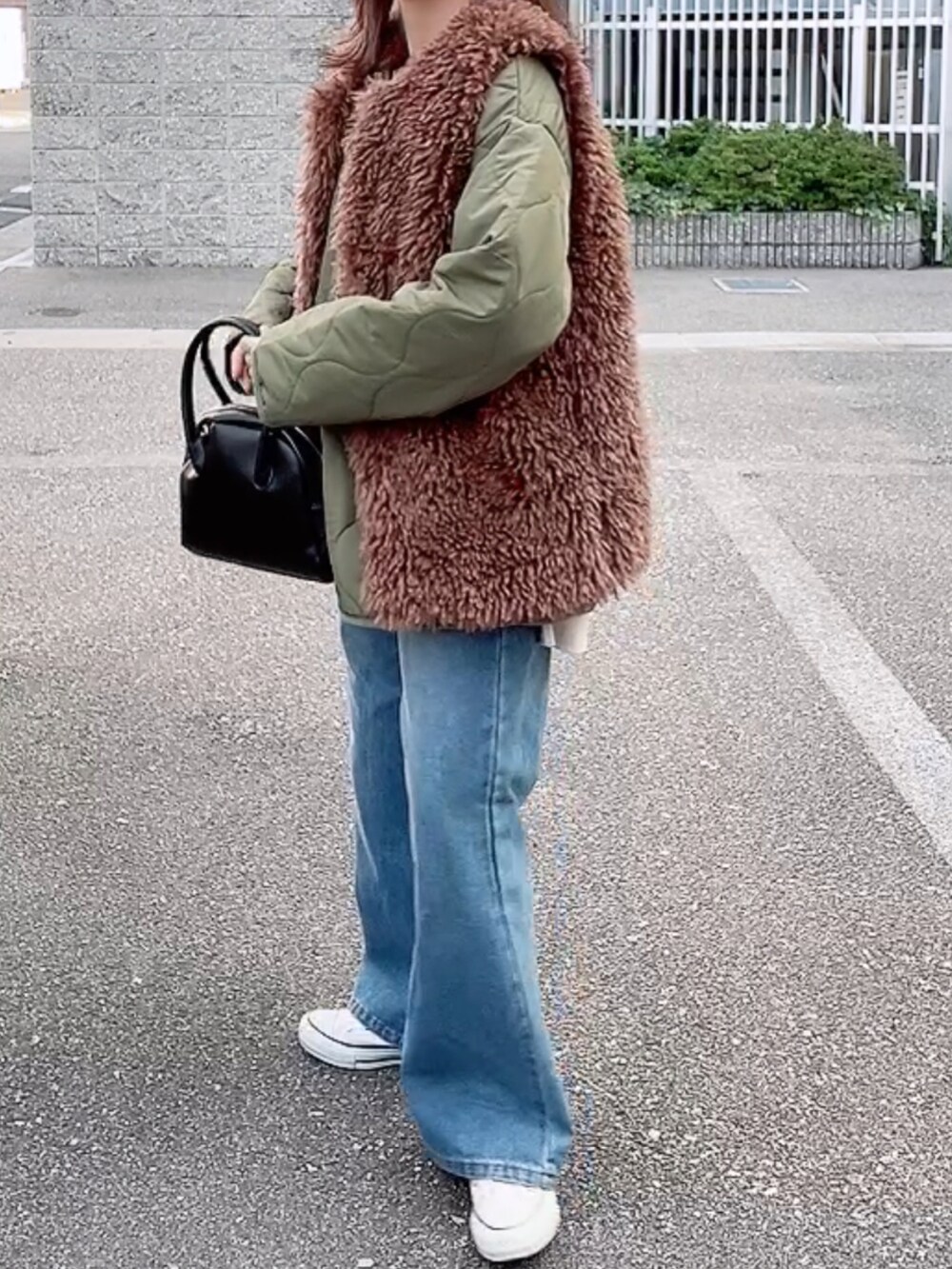 グリーン系のブルゾン、ブラック系のショルダーバッグ、ブルー系のデニムパンツを着用したレディースの秋コーディネートの3枚目の写真