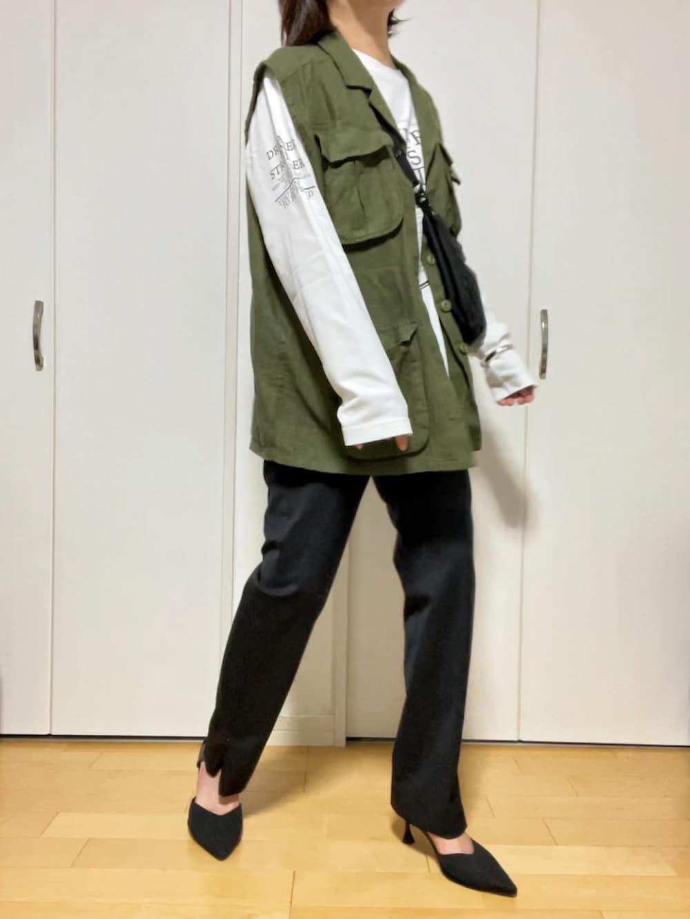 ホワイト系のTシャツ/カットソー、グリーン系のベスト、ブラック系のスラックスを着用したレディースの春コーディネートの2枚目の写真