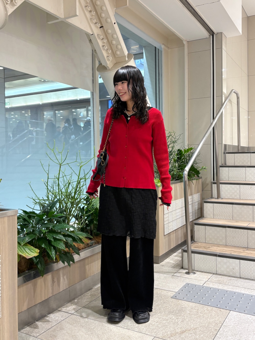 レッド系のカーディガン/ボレロ、ブラック系のショルダーバッグ、ブラック系のその他パンツを着用したレディースの冬コーディネートの2枚目の写真