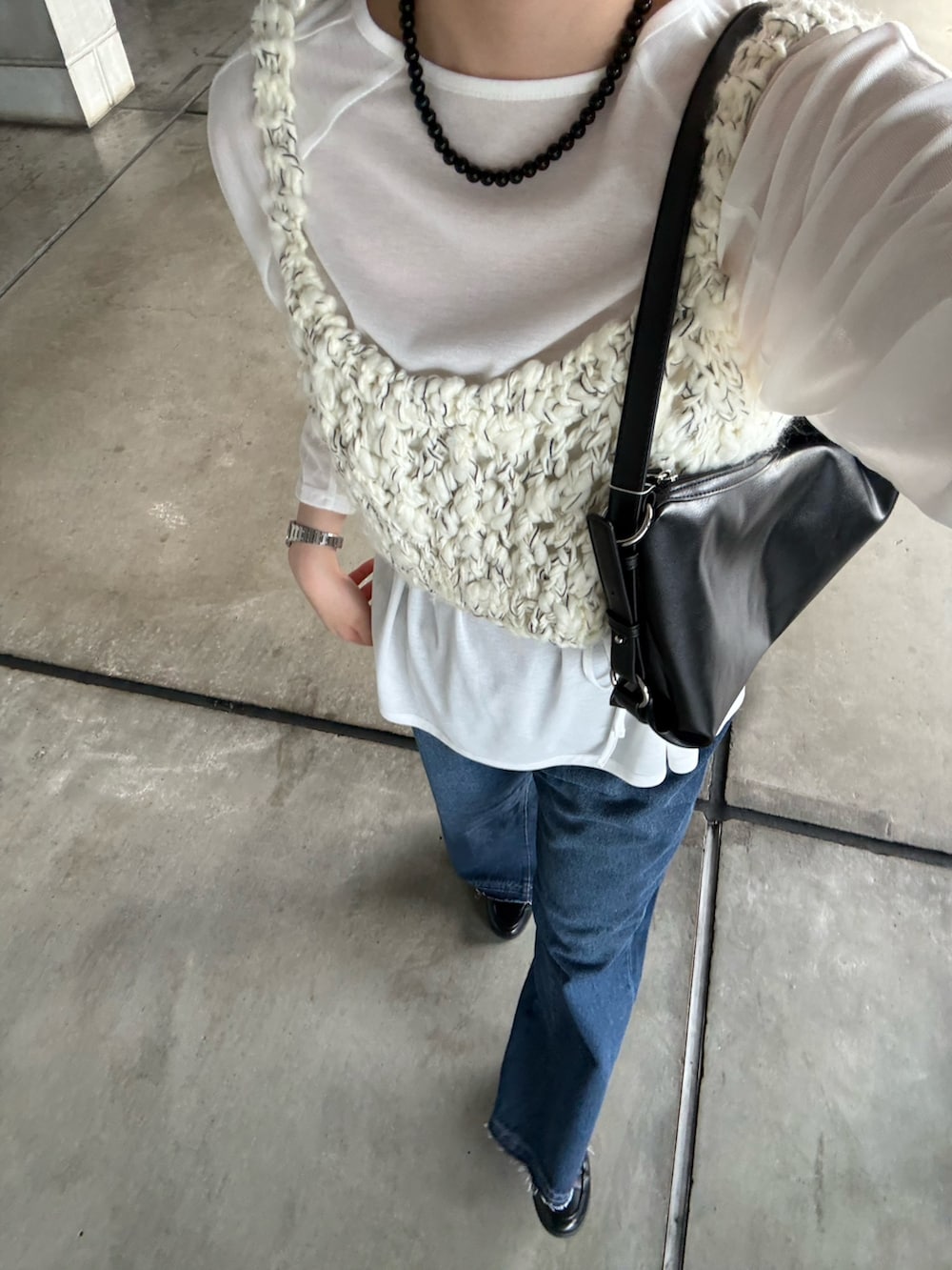 ブルー系のデニムパンツ、ブラック系のショルダーバッグ、ホワイト系のTシャツ/カットソーを着用したレディースの秋コーディネートの4枚目の写真