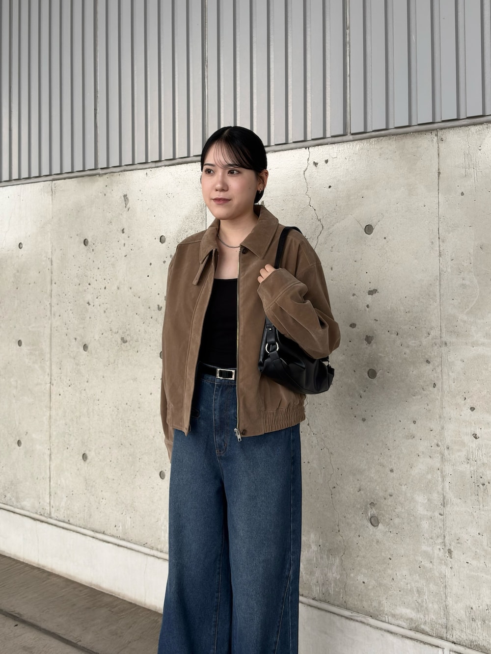 ブラック系のキャミソール、ブルー系のデニムパンツ、ベージュ系のブルゾンを着用したレディースの秋コーディネートの3枚目の写真