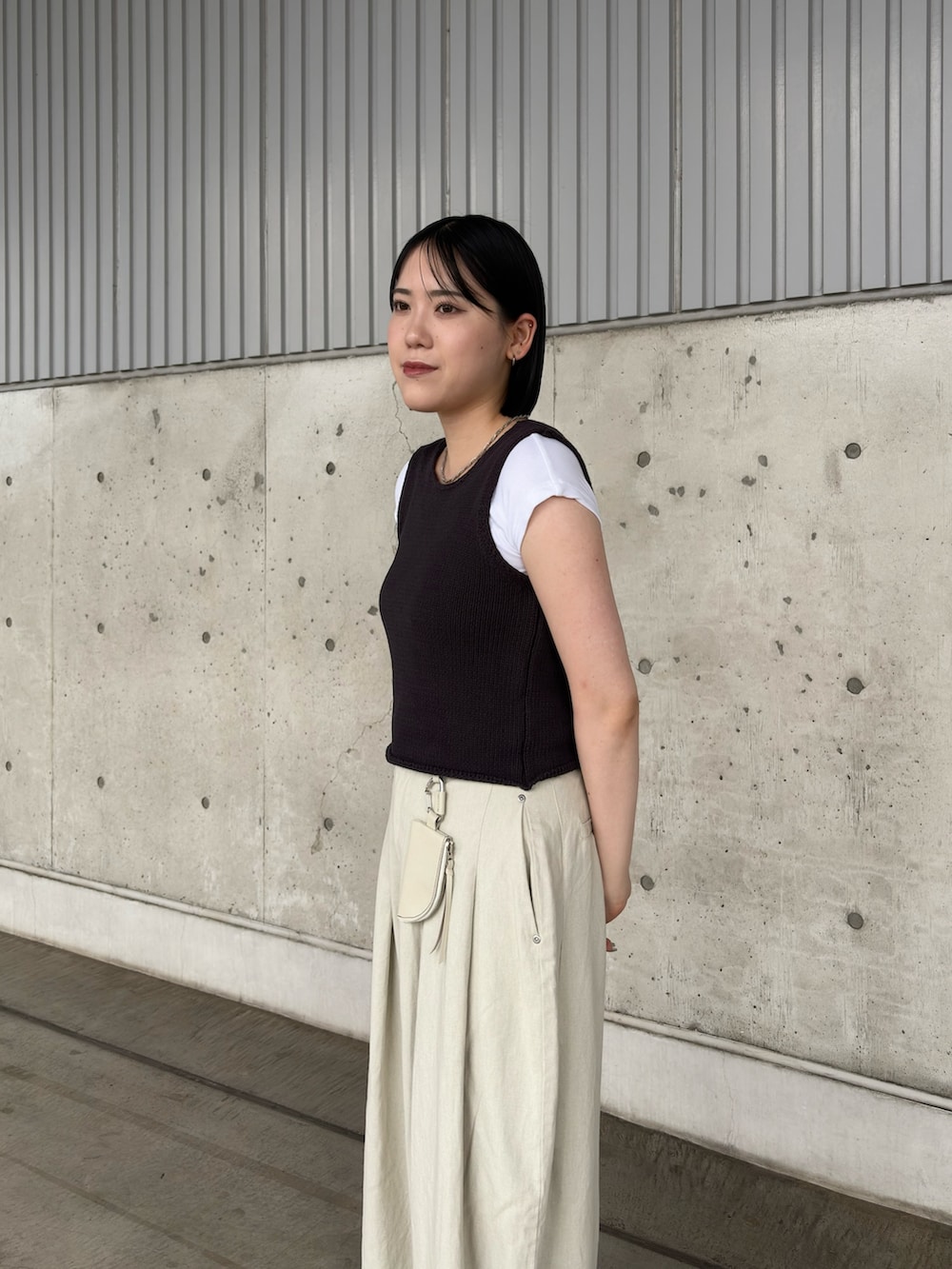 グレー系のベスト、ホワイト系のその他パンツ、ブラック系のサンダルを着用したレディースの夏コーディネートの2枚目の写真