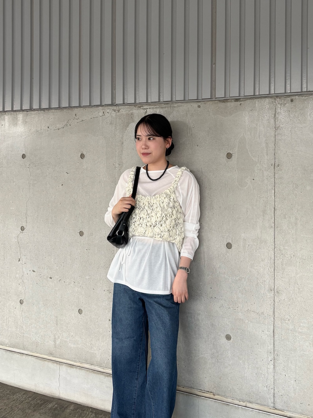 ブルー系のデニムパンツ、ブラック系のショルダーバッグ、ホワイト系のTシャツ/カットソーを着用したレディースの秋コーディネートの3枚目の写真