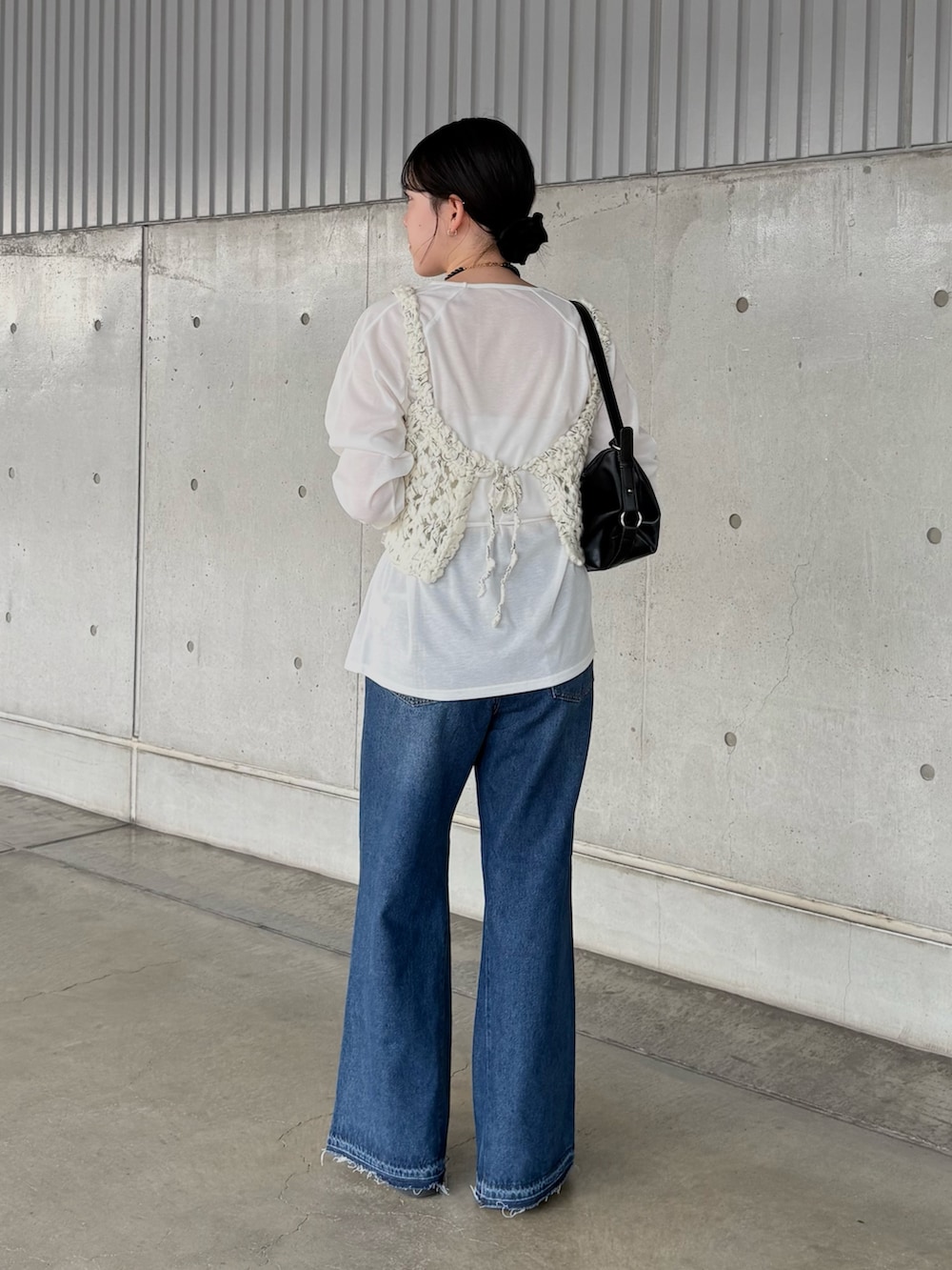 ブルー系のデニムパンツ、ブラック系のショルダーバッグ、ホワイト系のTシャツ/カットソーを着用したレディースの秋コーディネートの2枚目の写真
