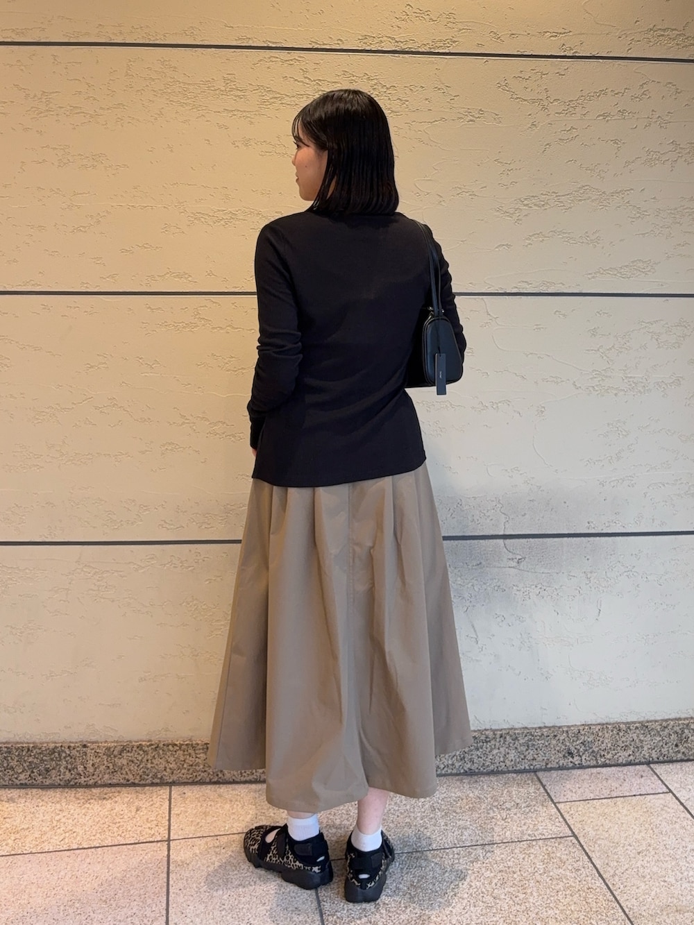 ベージュ系のスカート、その他のスニーカー、ブラック系のカーディガン/ボレロを着用したレディースの秋コーディネートの2枚目の写真