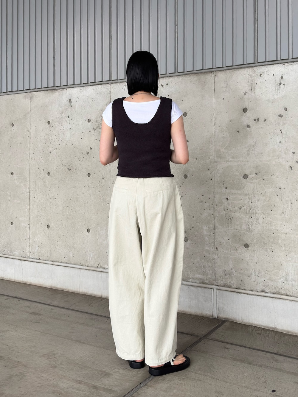 グレー系のベスト、ホワイト系のその他パンツ、ブラック系のサンダルを着用したレディースの夏コーディネートの3枚目の写真