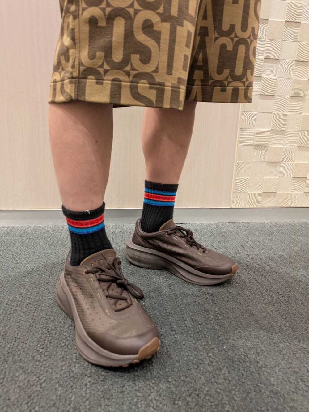 ブラウン系のポロシャツ、ブラウン系のその他パンツ、ブラック系のスニーカーを着用したメンズの夏コーディネートの5枚目の写真