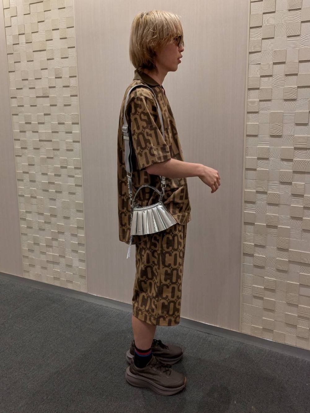 ブラウン系のポロシャツ、ブラウン系のその他パンツ、ブラック系のスニーカーを着用したメンズの夏コーディネートの2枚目の写真