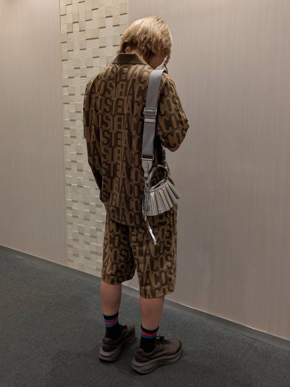 ブラウン系のポロシャツ、ブラウン系のその他パンツ、ブラック系のスニーカーを着用したメンズの夏コーディネートの3枚目の写真