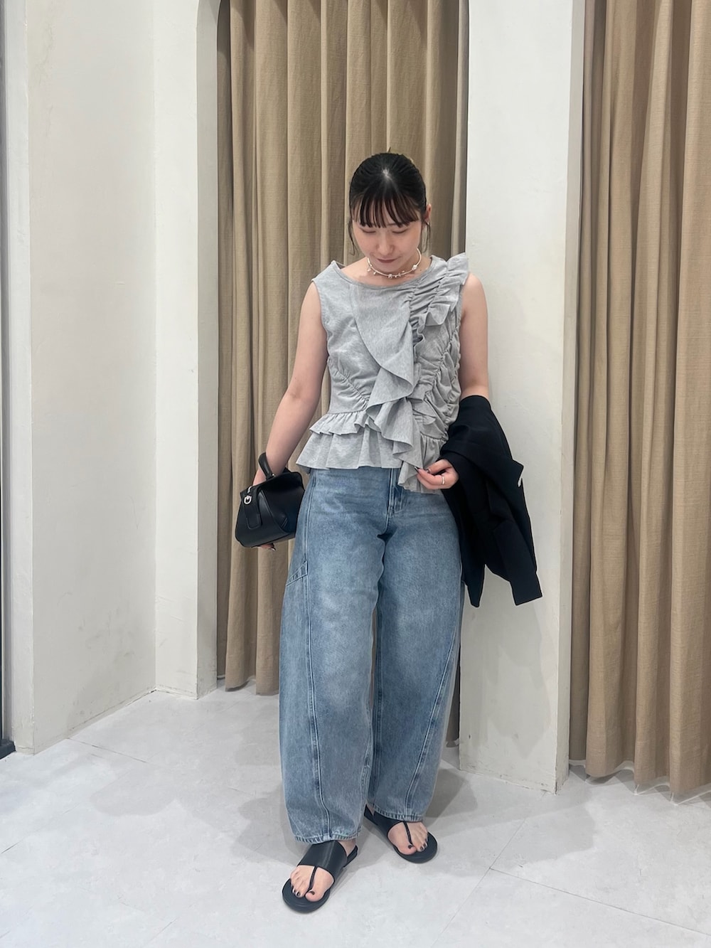 グレー系のTシャツ/カットソー、ブラック系のテーラードジャケット、ブルー系のデニムパンツを着用したレディースの春コーディネートの2枚目の写真