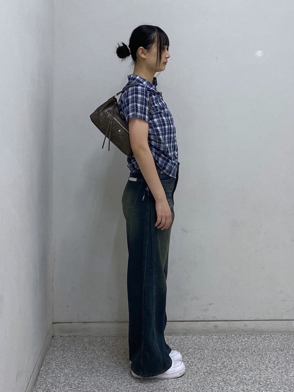 ブルー系のデニムパンツ、ブルー系のシャツ/ブラウス、ブラウン系のショルダーバッグを着用したレディースの夏コーディネートの2枚目の写真