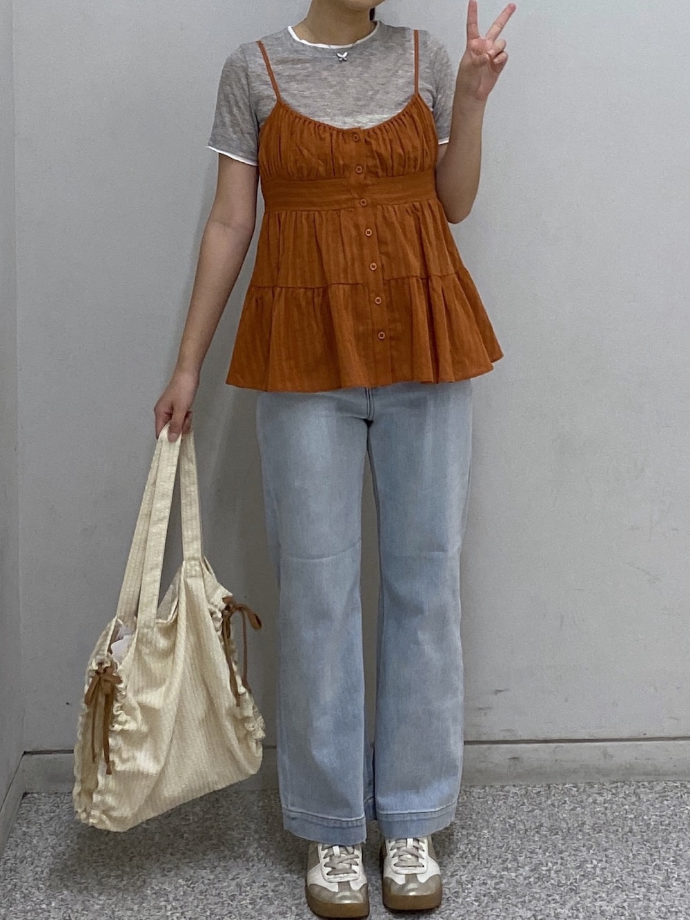 ブラウン系のシャツ/ブラウス、グレー系のTシャツ/カットソー、ブルー系のデニムパンツを着用したレディースの春コーディネートの2枚目の写真