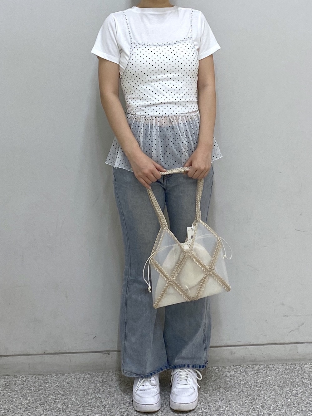 ホワイト系のTシャツ/カットソー、ブルー系のデニムパンツ、ベージュ系のトートバッグを着用したレディースの夏コーディネートの2枚目の写真