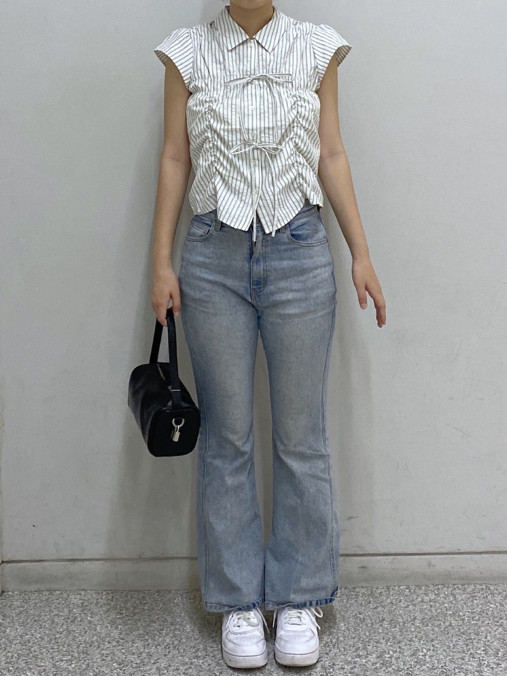 ブルー系のデニムパンツ、ブラック系のハンドバッグ、ホワイト系のシャツ/ブラウスを着用したレディースの夏コーディネートの2枚目の写真