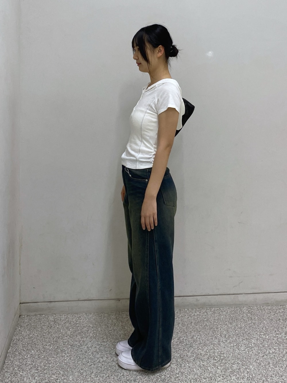 ブルー系のデニムパンツ、ブラック系のショルダーバッグ、ホワイト系のTシャツ/カットソーを着用したレディースの夏コーディネートの3枚目の写真