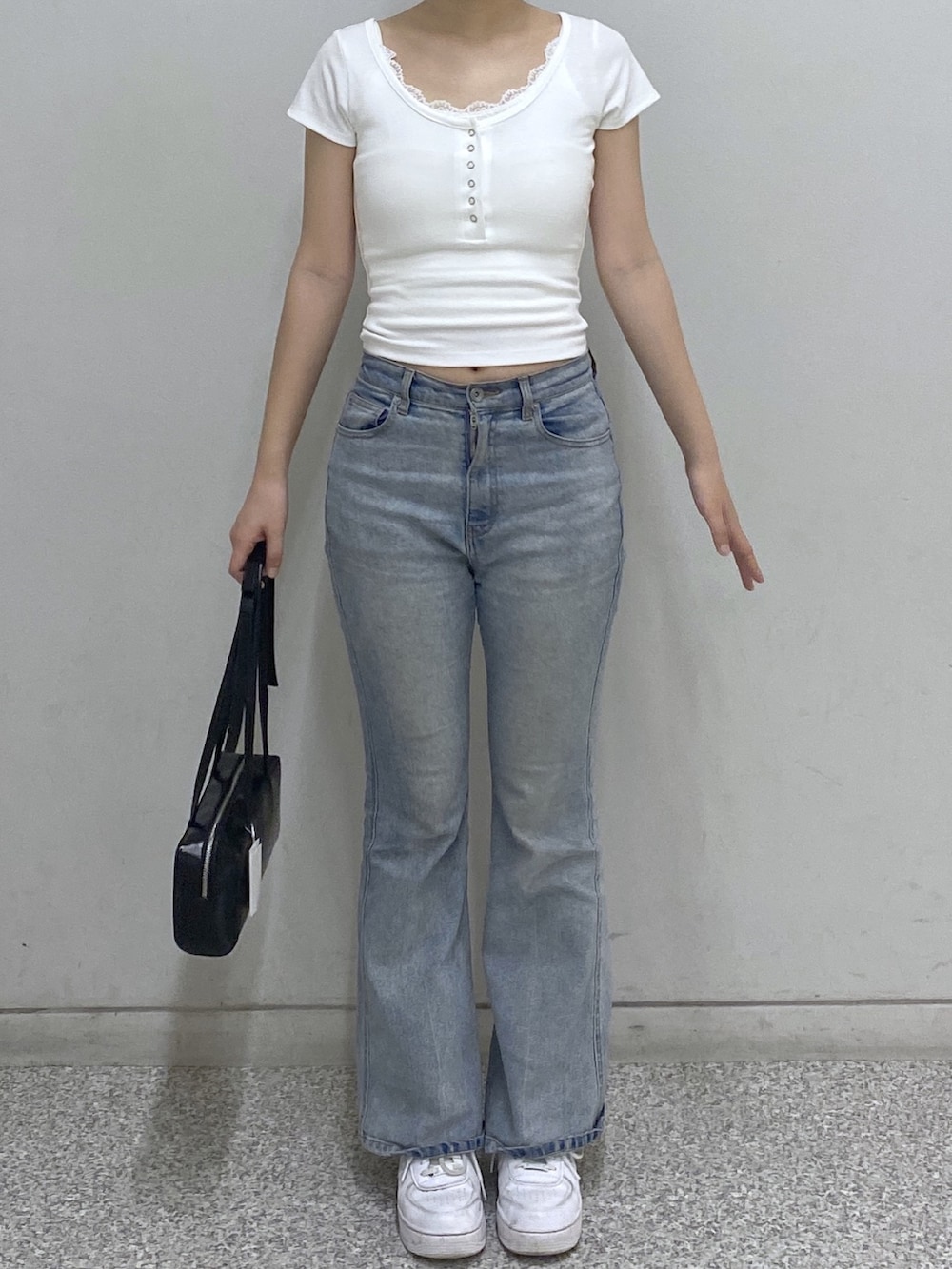 ブルー系のデニムパンツ、ブラック系のショルダーバッグ、ホワイト系のTシャツ/カットソーを着用したレディースの夏コーディネートの2枚目の写真