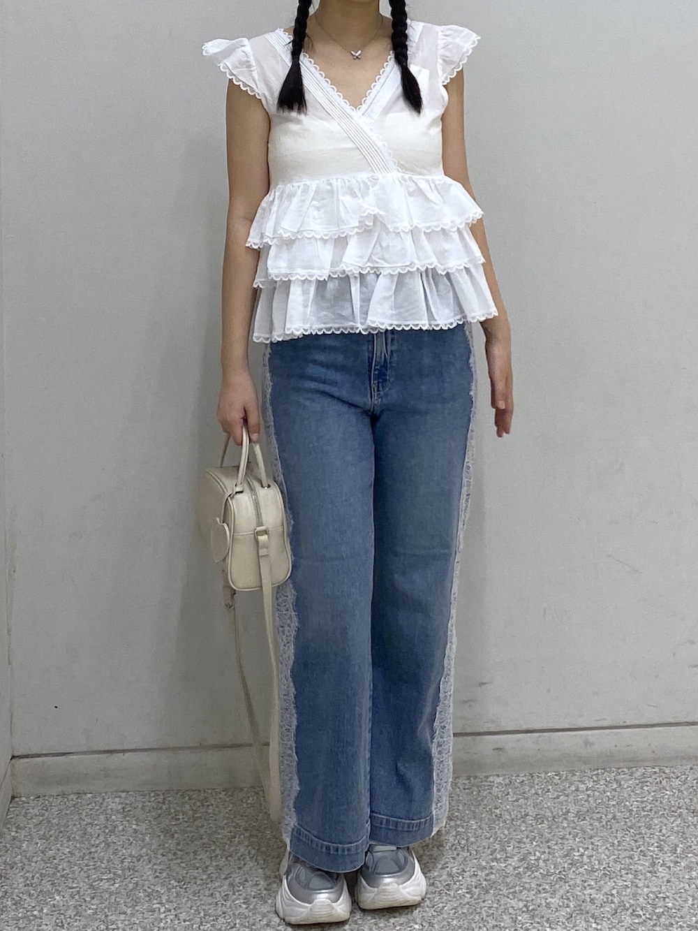 ブルー系のデニムパンツ、ホワイト系のボストンバッグ、ホワイト系のシャツ/ブラウスを着用したレディースの夏コーディネートの2枚目の写真