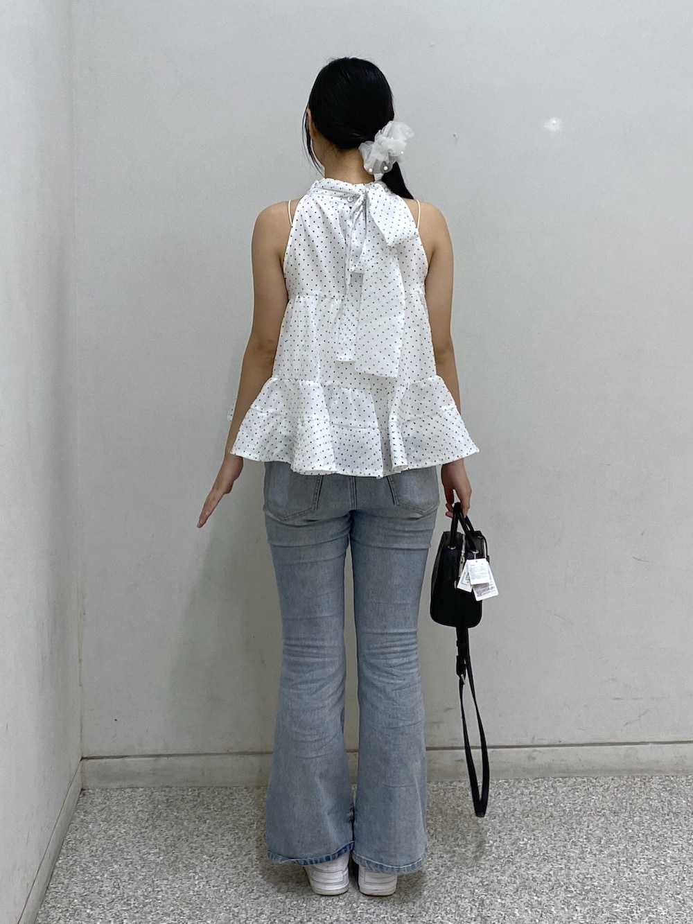 ブルー系のデニムパンツ、ブラック系のボストンバッグ、ホワイト系のシャツ/ブラウスを着用したレディースの夏コーディネートの2枚目の写真